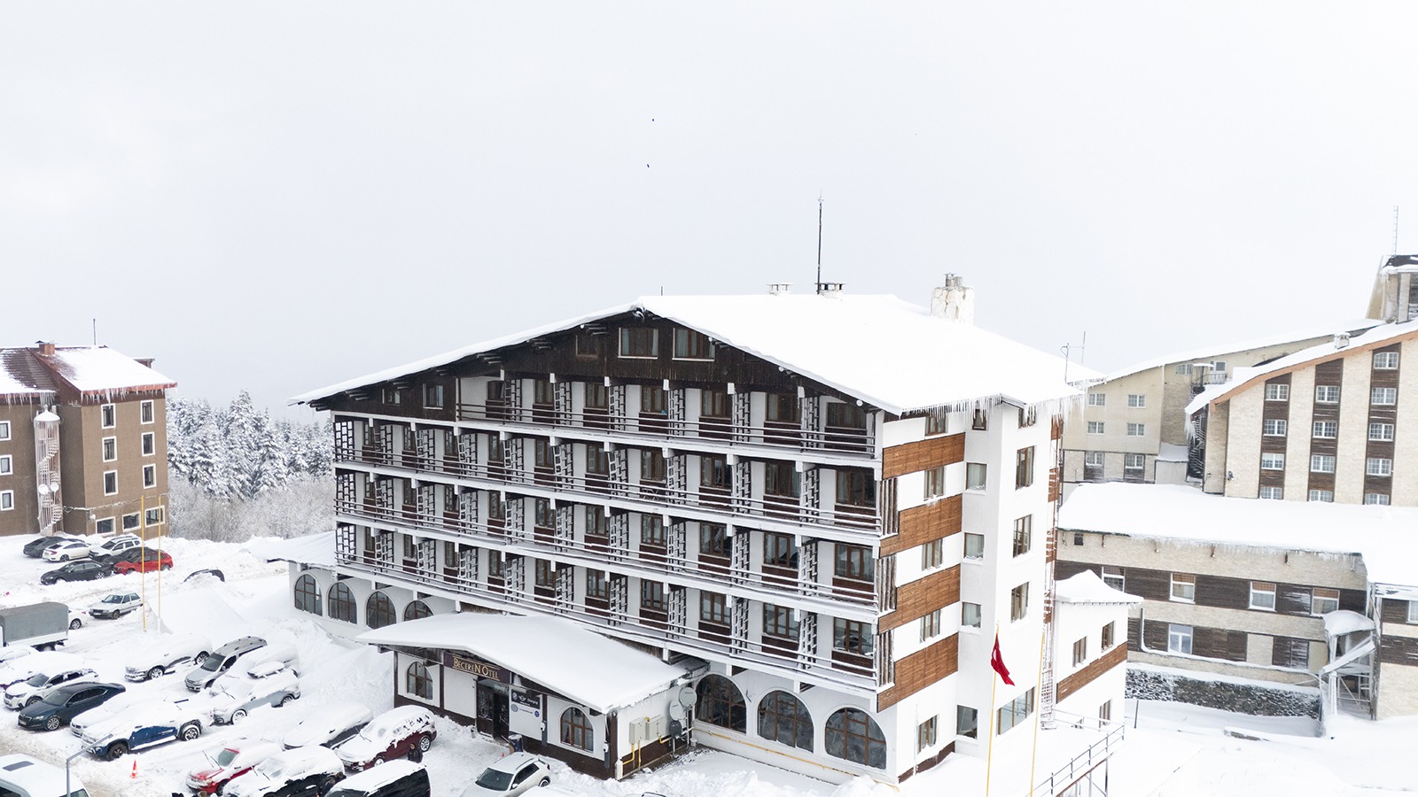 Beceren Otel’s signed facade under snow, with parked cars and neighboring buildings in Uludağ